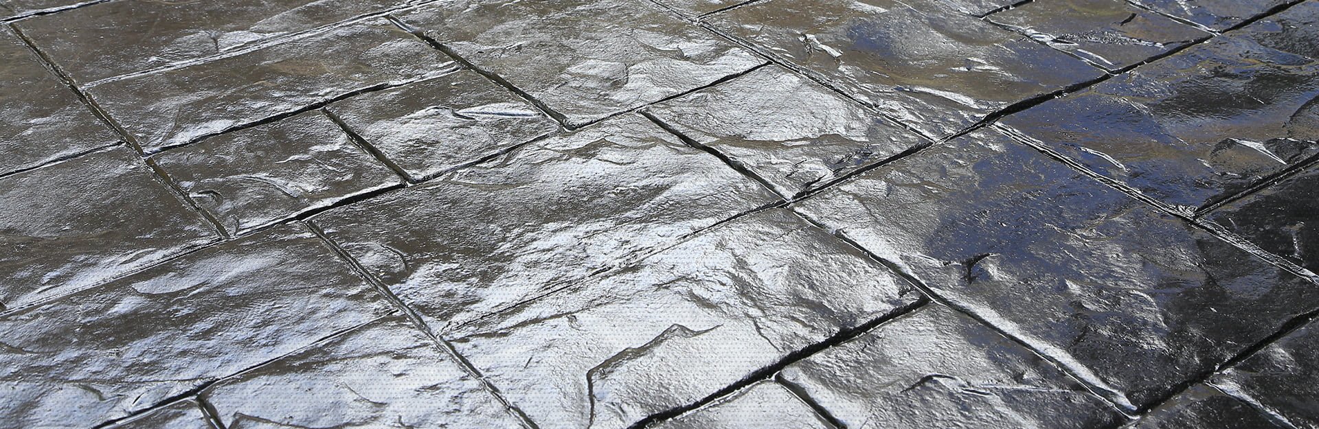New concrete that was laid down and dried with a stamped pattern that makes the concrete appear as shiny bricks.